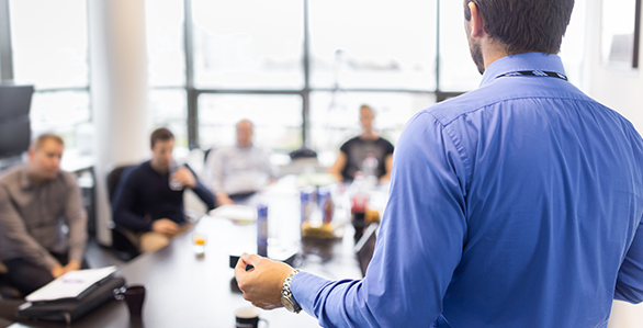 Instructor leading training to a group of people seated around a table